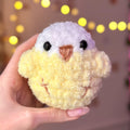 Plush toy resembling a bird held in a hand with a blurred light background